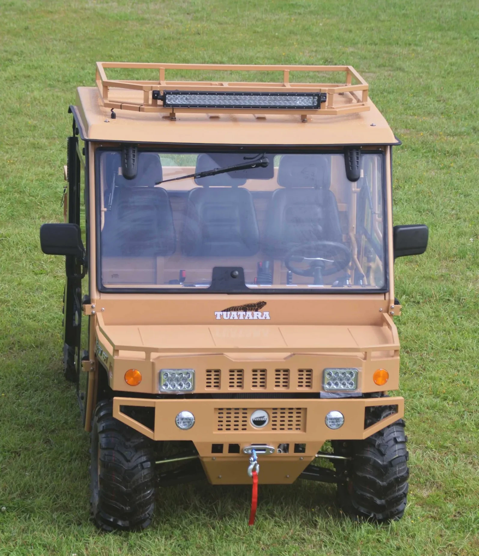 A tan vehicle is parked in the grass.