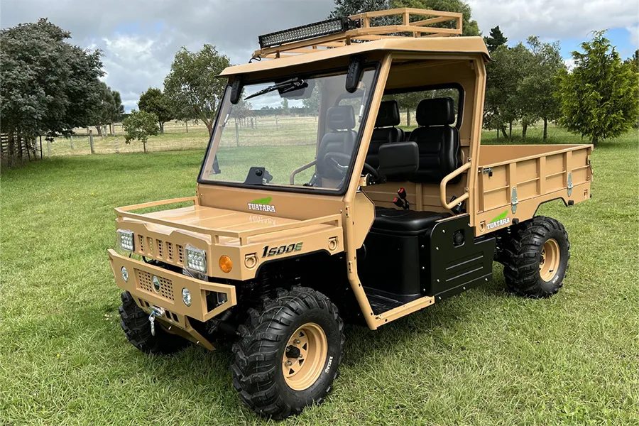 A tan utility vehicle parked in the grass.
